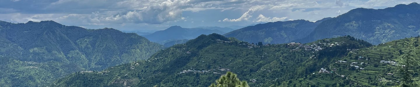 View of beautiful mountain ranges in Himachal Pradesh  with small groups of houses in the distance.