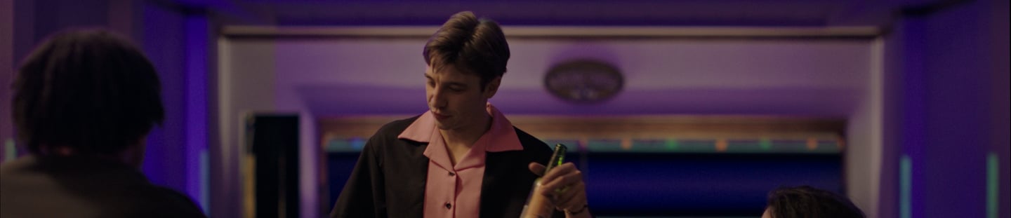 a man in a bowling shirt is holding a bottle of beer