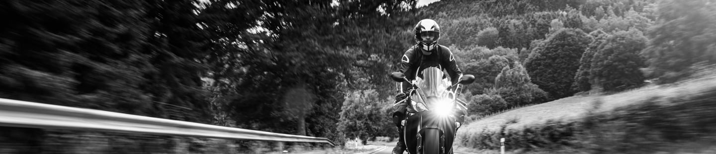 Picture of motorcycle head as it rides down a road with its headlight on