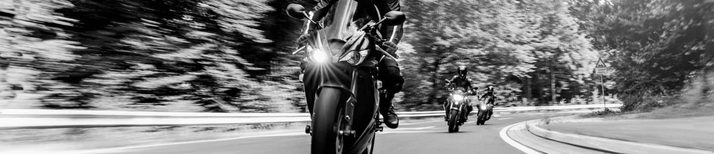 front view of three motorcycles travelling around a left hand bend one behind the other