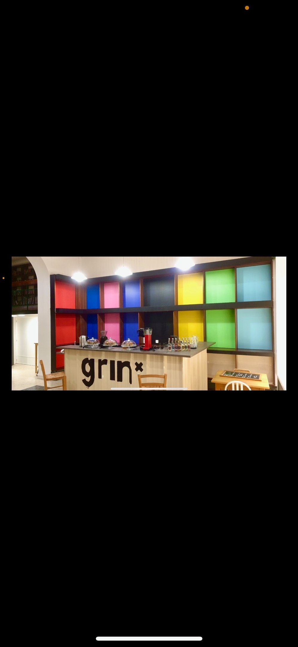 un bar avec une fresque avec des triangles de couleurs vives et des inscriptions noir et blanches