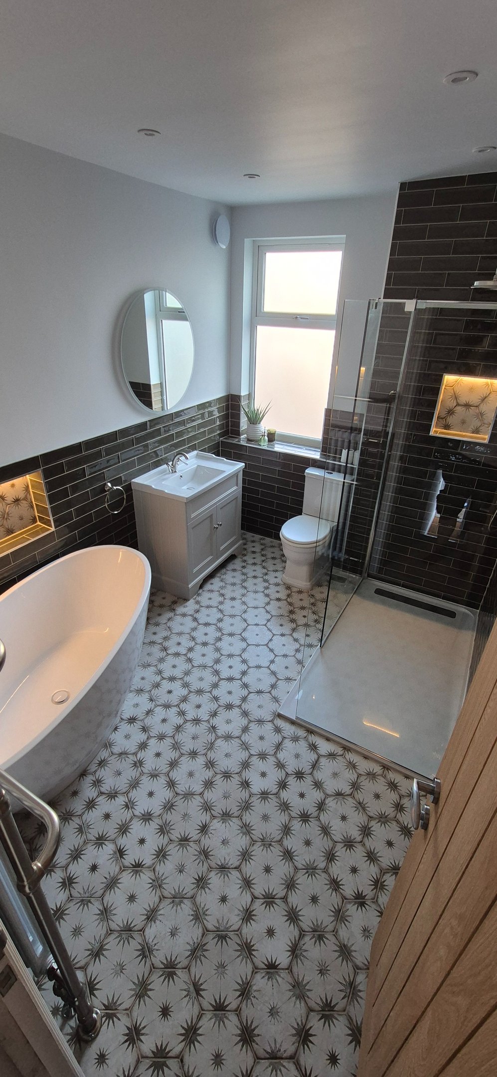 Modern bathroom with a freestanding bathtub, glass walk-in shower, and patterned star tile flooring.