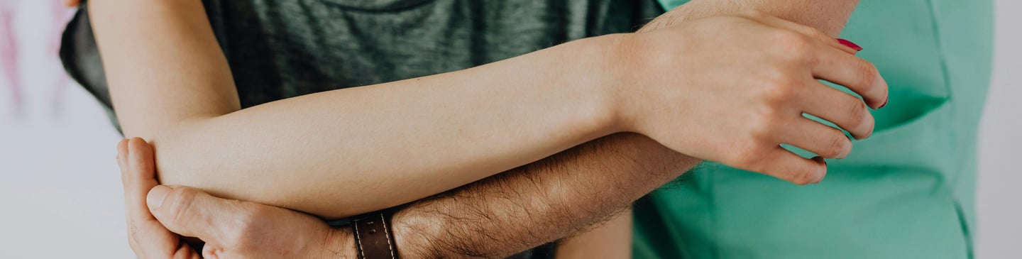 Man supporting woman's arm in treatment.