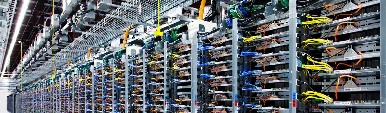 Modern AI data center with organized server racks and complex colorful network cabling.