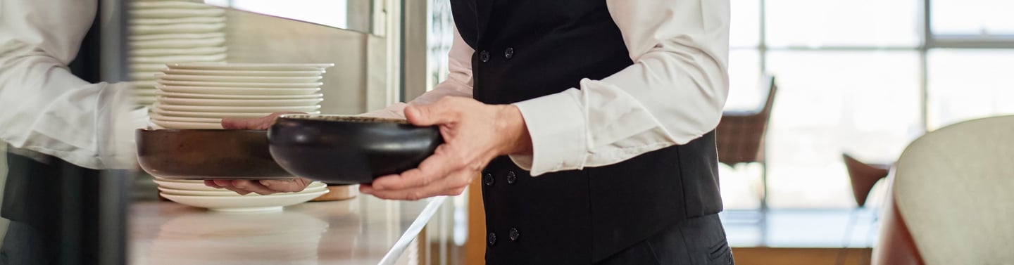 camarero recogiendo platos cerca de cocina