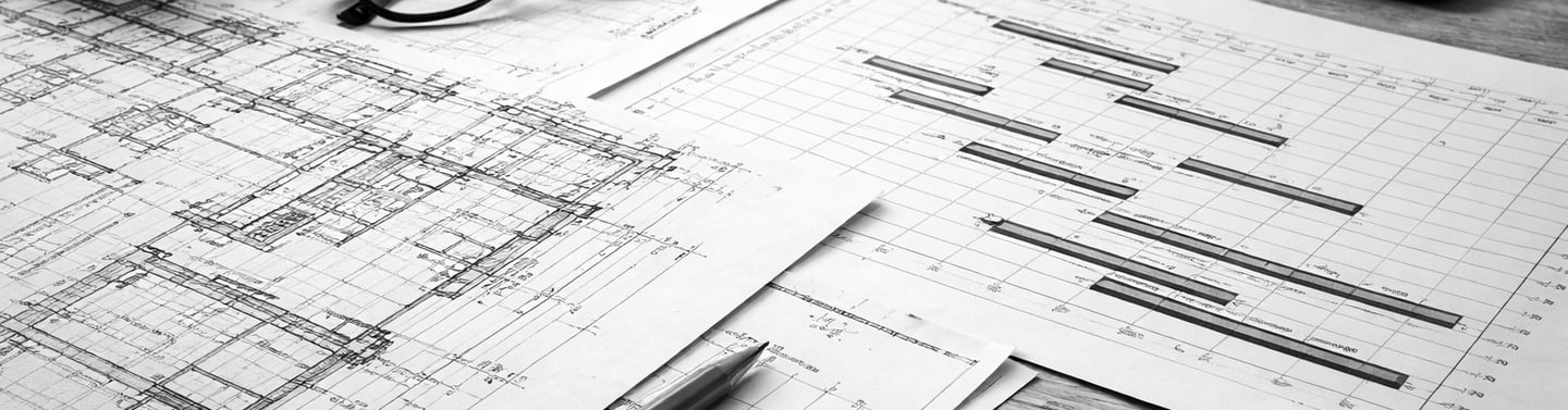 Plantas arquitetônicas e documentos financeiros sendo analisados sobre uma mesa durante a avaliação 