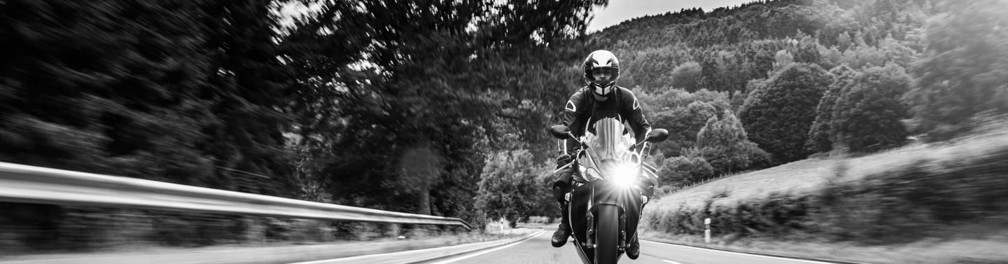 Picture of motorcycle head as it rides down a road with its headlight on
