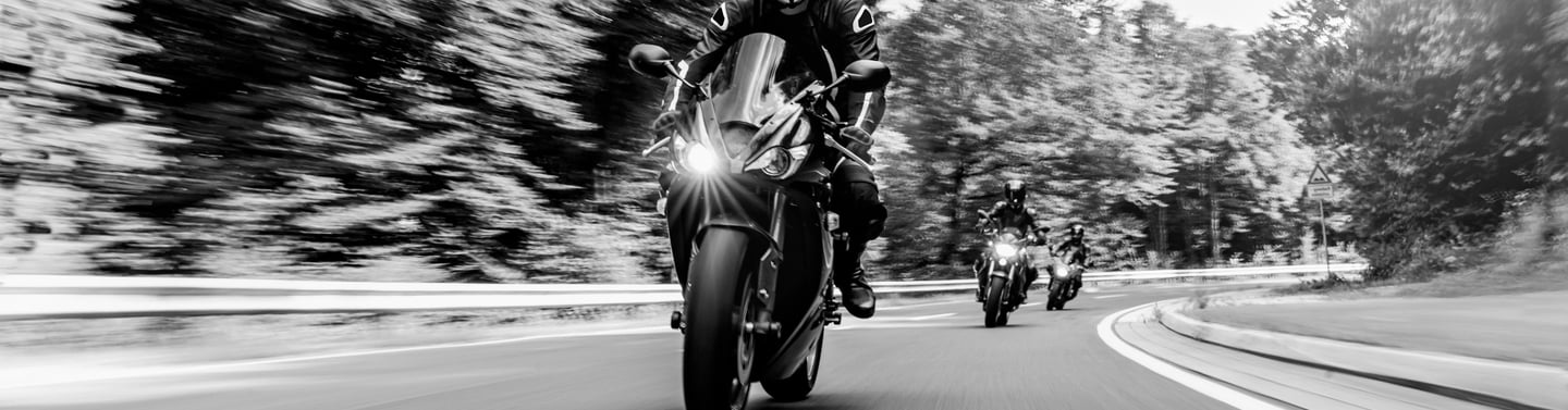 front view of three motorcycles travelling around a left hand bend one behind the other