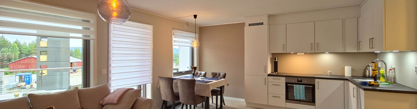 Modern open-concept living room and kitchen with white cabinets and a dining table.