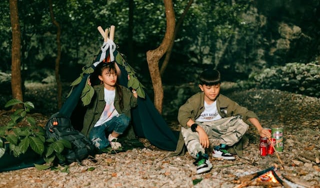 two kids sitting on a blanket in a tent, tips for travelling with kids