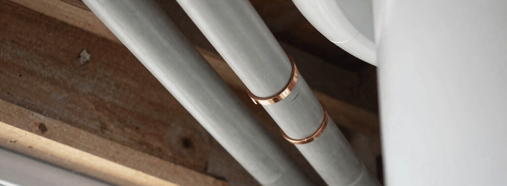 Grey Poly B water pipes with copper crimp fittings running along a basement ceiling in Langley home