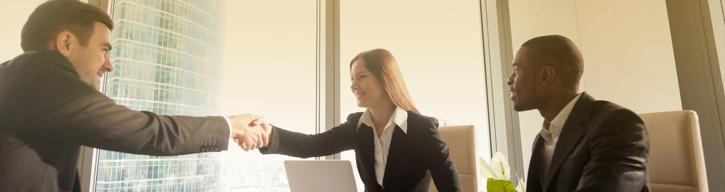 a man and woman shaking hands in a meeting room