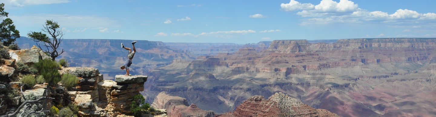 a man hand standing on a cliff overlooking a vast view of the grand canyon
