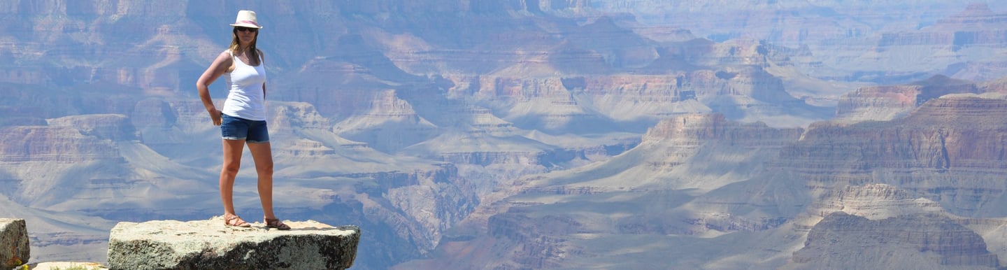 a woman standing on a cliff overlooking the grand canyon