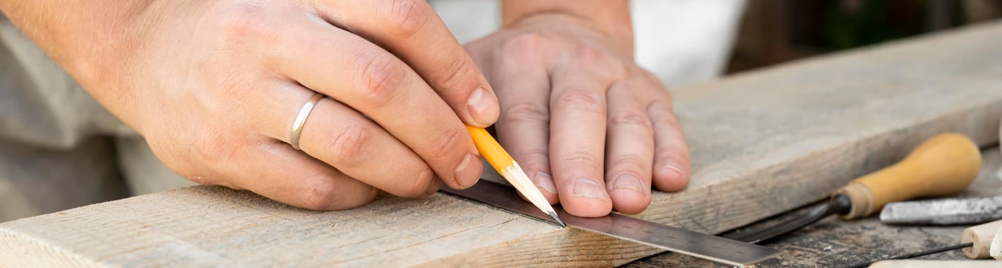 gros plan main traçant une planche de bois