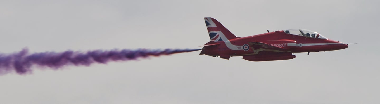 Close of up a Red Arrows plane with a trail of purple smoke at Goodwood Festival of Speed