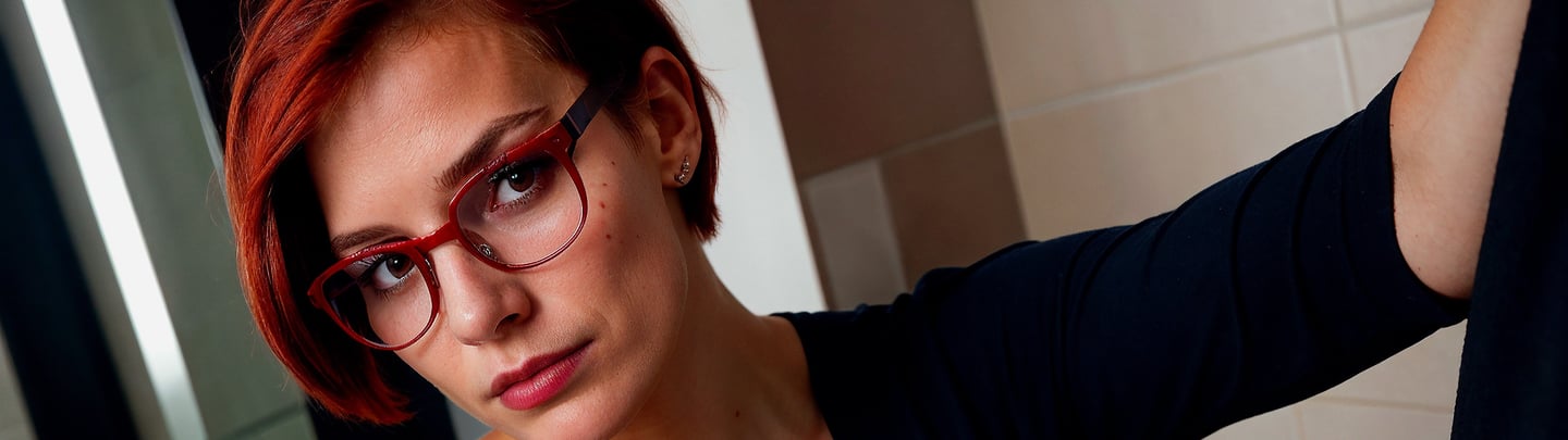 a woman with red hair and glasses on her face