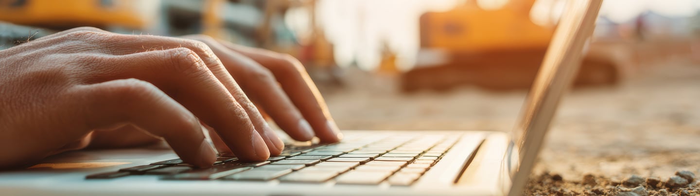 Contractor using a laptop at a construction site, showing digital bookkeeping and job management.