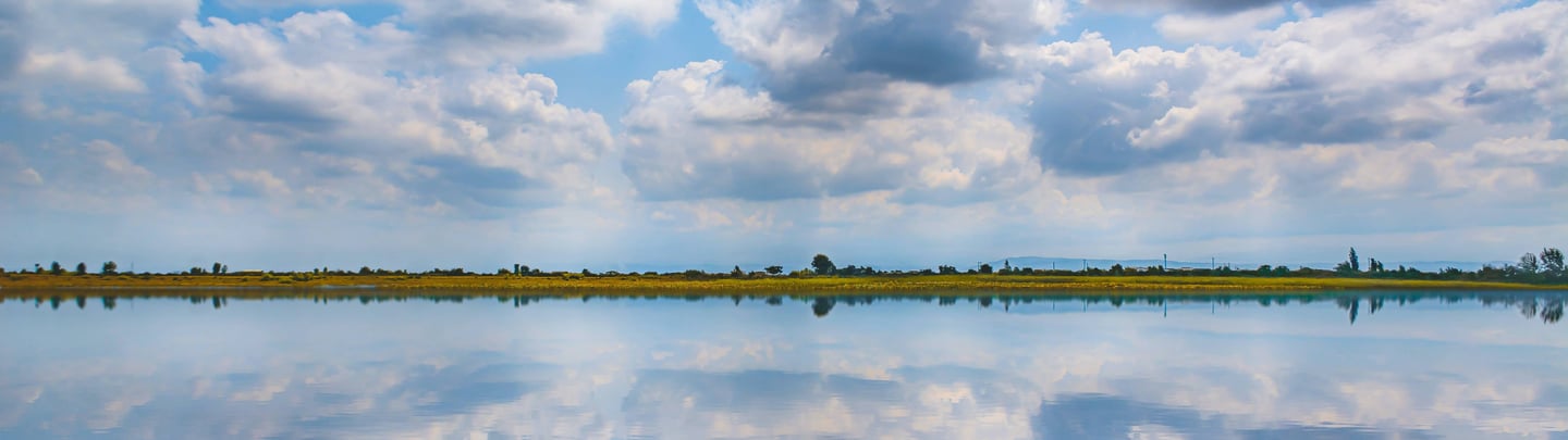 A horizon of the sky and river meeting with a thin layer of earth in between