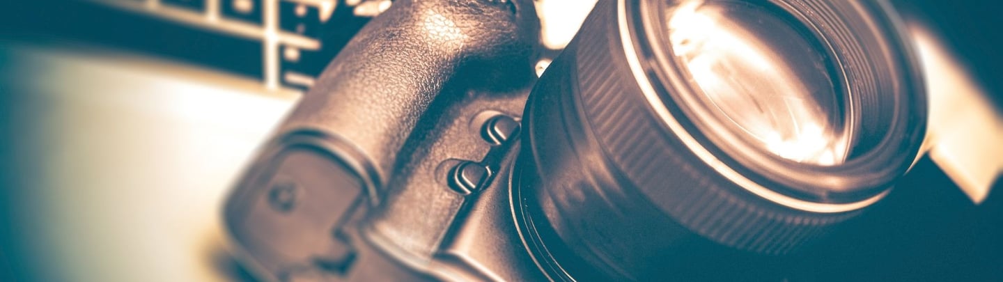 A modern DSLR camera paired with an interchangeable lens, arranged on a sleek surface to highlight learning photography