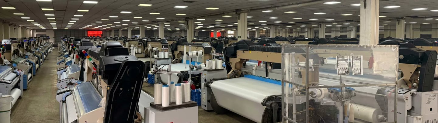 textile factory producing woven fabrics with industrial weaving equipment