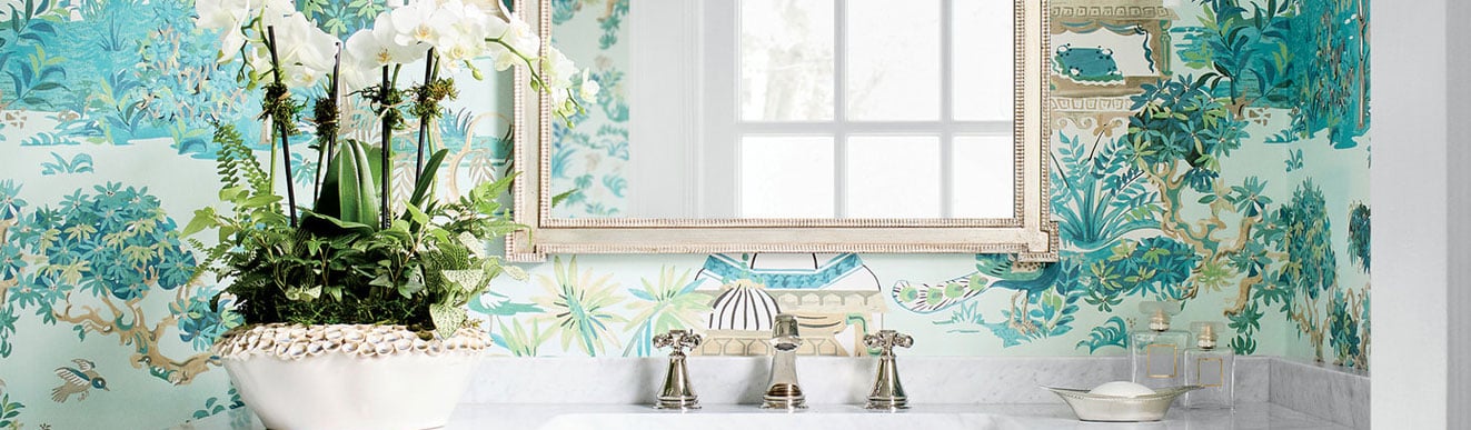 Elegant bathroom vanity with white marble top, white orchid plant, and teal chinoiserie wallpaper.