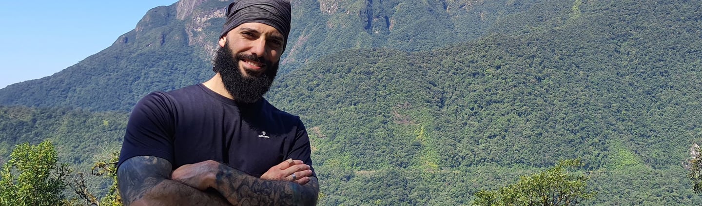 um personal trainer de braço cruzados em frente a montanha