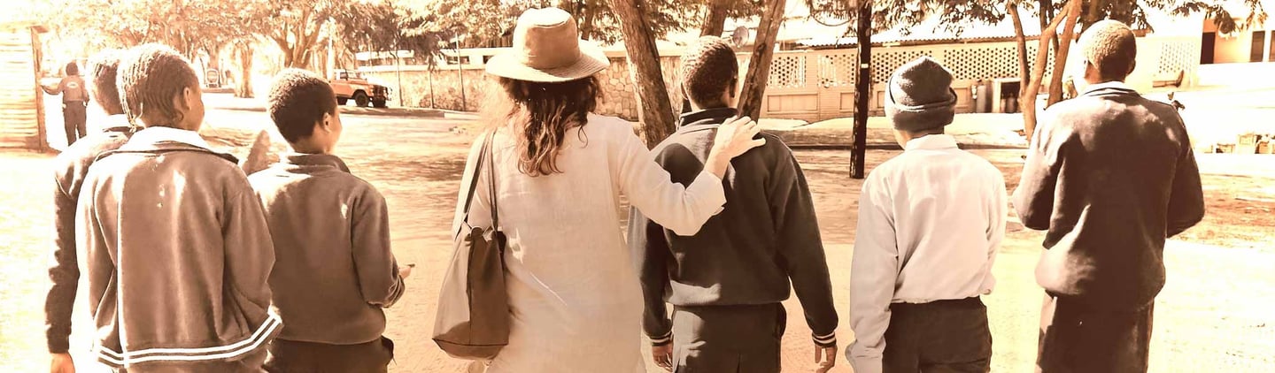 School children walking away with teachers arm on the Childs shoulder