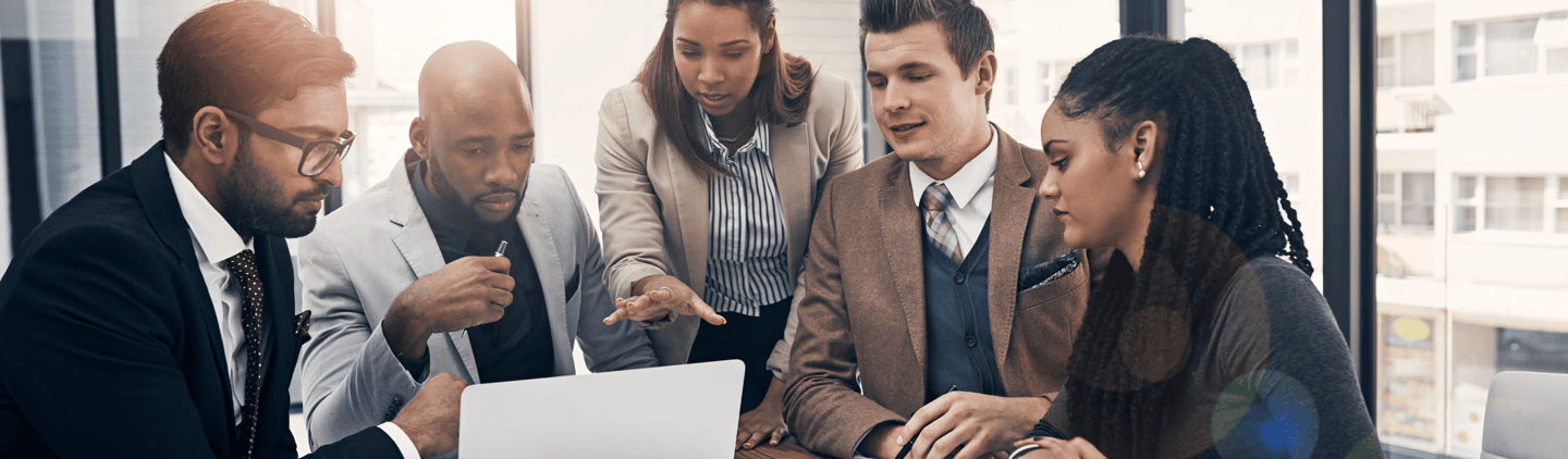 Diverse business team collaborating around a laptop, analyzing IT solutions and discussing the best technology strategy for t