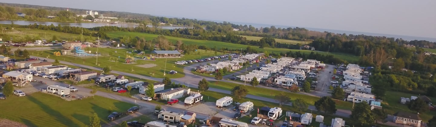 Aerial view of a lakeside RV park and campground with many campers, trailers, and outdoor recreation areas.
