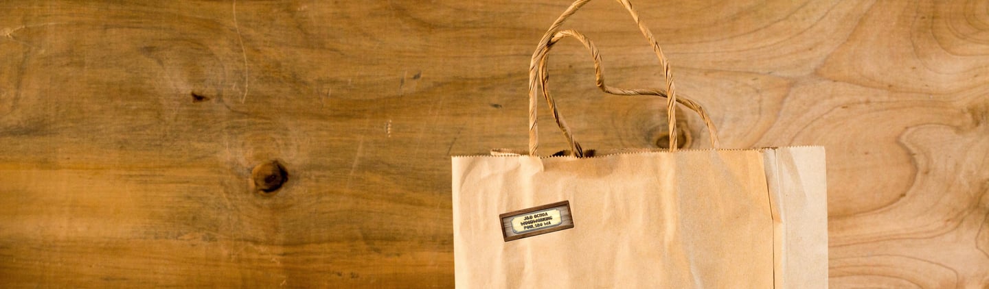 Brown paper shopping bag with J & D Ochoa Woodworking Logo sticker