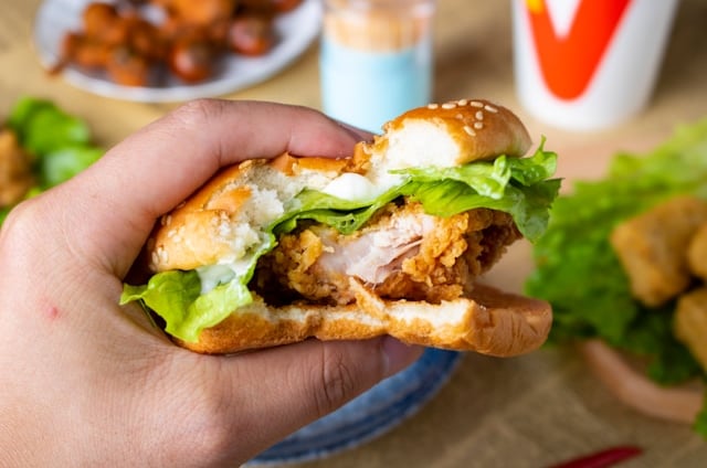 Chick-fil-A® catering menu, a person holding a burger with chicken and lettuce