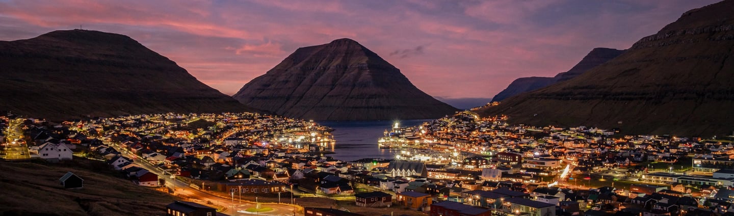 Sunset casts vibrant hues over Klaksvík, a picturesque town in the Faroe Islands, creating a serene evening atmosphere.