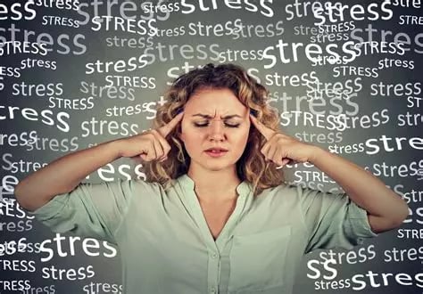Femme blonde cheveux longs yeux fermés index sur les tempes en situation de stress