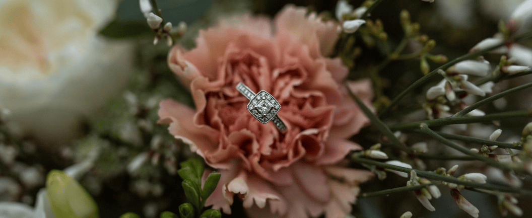 a diamond ring with a diamond ring on top of a bouquet of flowers