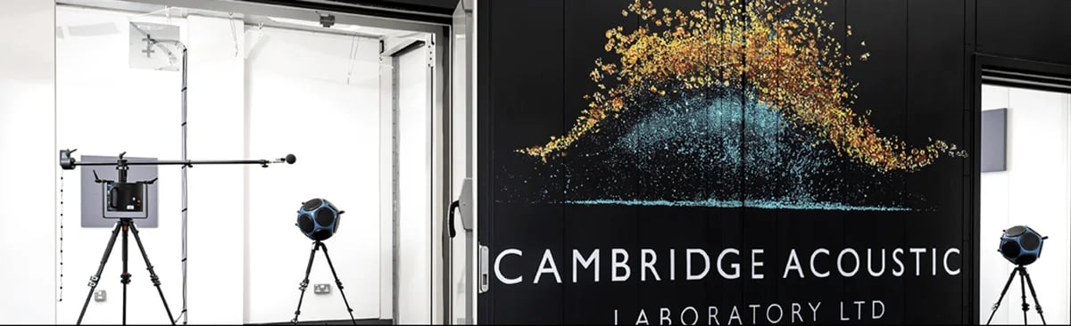 Large logo mural on black background flanked by professional audio equipment in white rooms