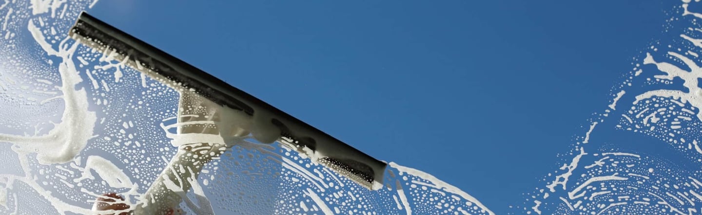 A squeegee smoothly glides over glass surface, leaving behind a streak-free shine