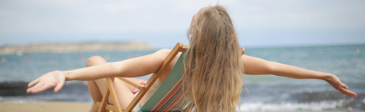 Woman in Blue and Brown Bikini Sitting on Brown Wooden Folding Chair on Beach