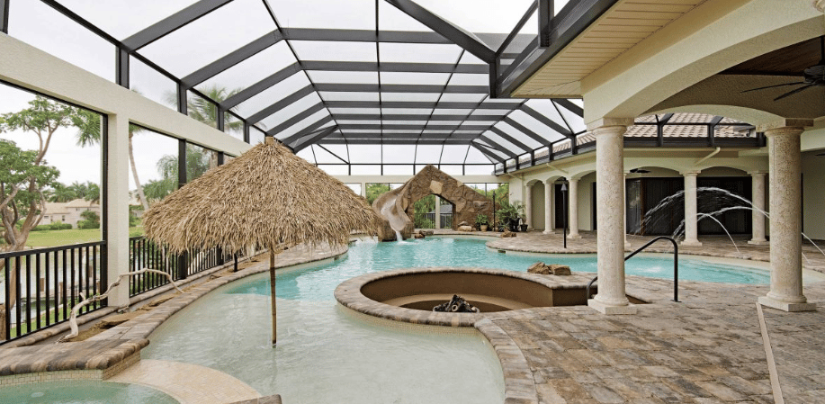 Tropical lagoon pool with light aqua water, tan stone tiling, rock slide and curved spa set under an