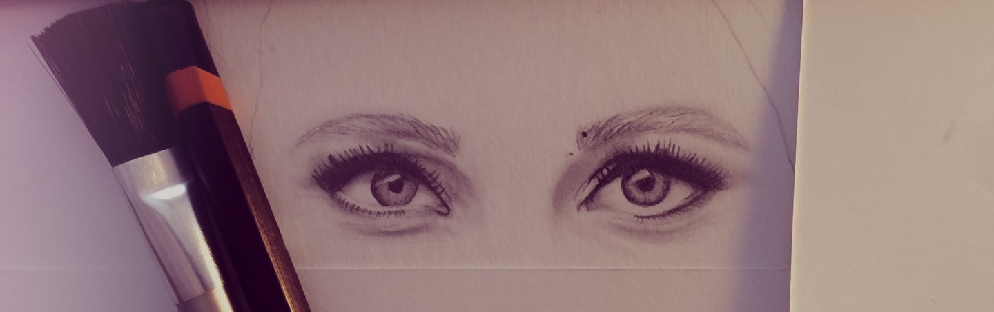 A drawing of human eyes with pencil and brush next to it