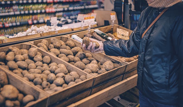 person selecting potatoes at grocery store