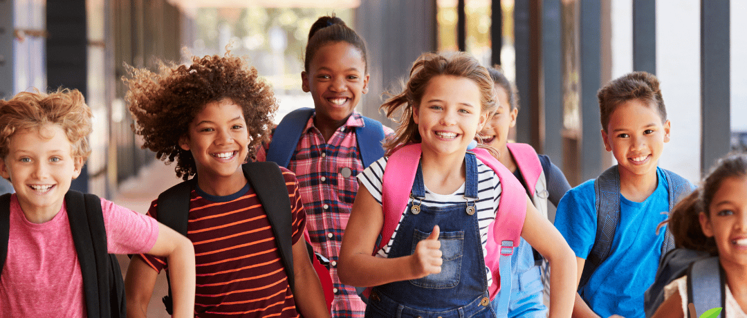 A group of excited children running along a hallway