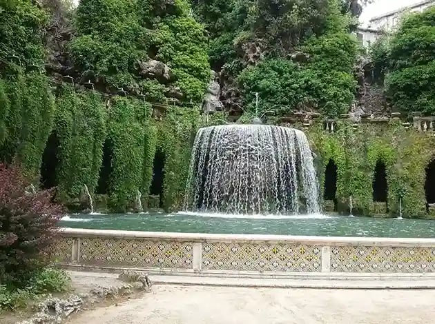 Cascade se jetant dans 1 bassin et entourée de plantes tombantes et de colonnes