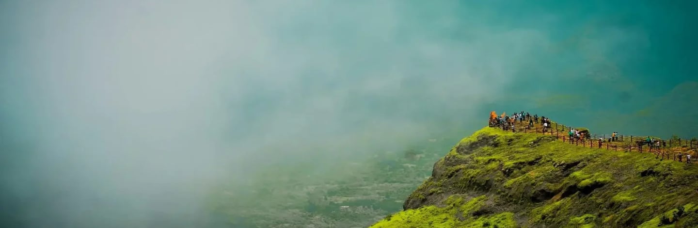 Lush green mountains and valleys covered in deep mist at Raigad Fort during the monsoon season.