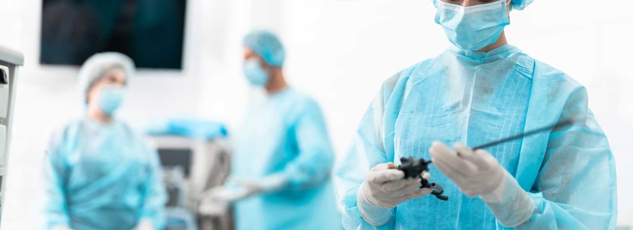 a woman in a blue gown and surgical equipment proceeding arthroscopy