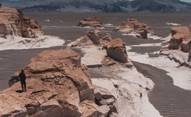 a person standing on a rock formation in the desert