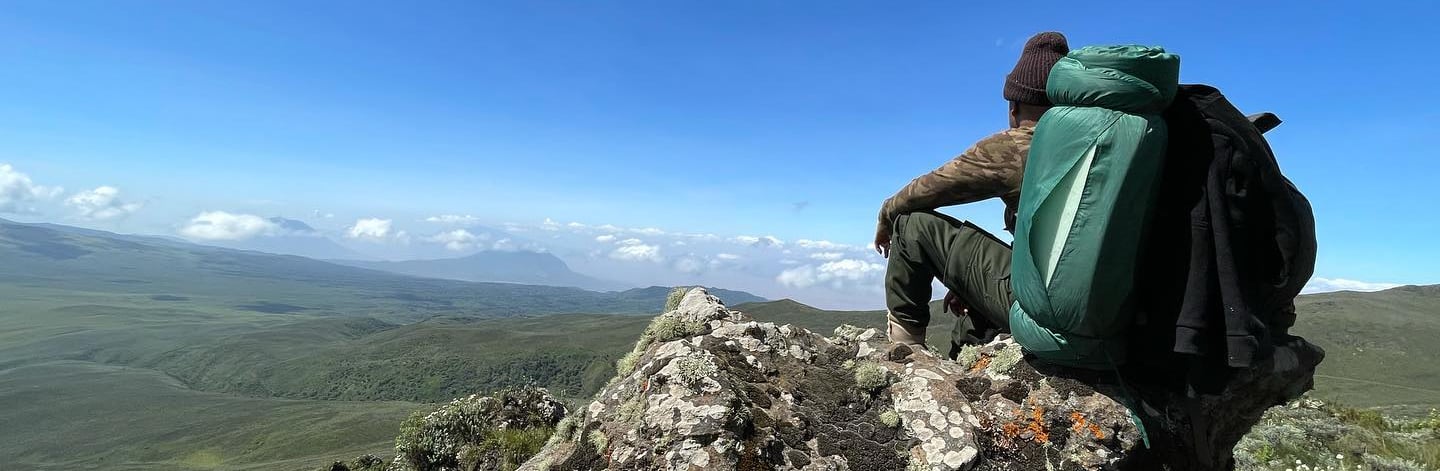 a man sitting on a rock with a backpack on top of it