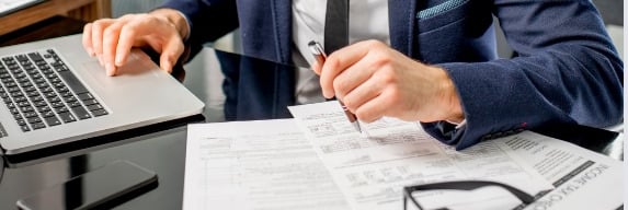 a man in a suit and tie is sitting at a desk with a laptop