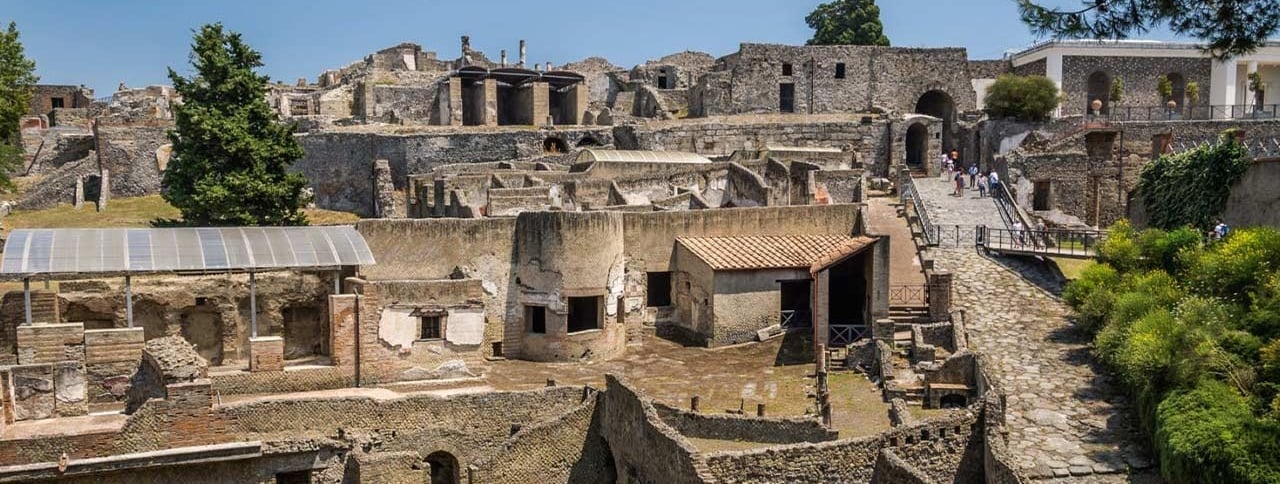 Scavi di Pompei: vista su un’antica strada con rovine ben conservate e il Vesuvio sullo sfondo