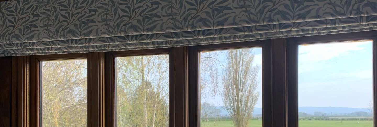A roman blind in a leafy fabric designed to work with the view of open fields